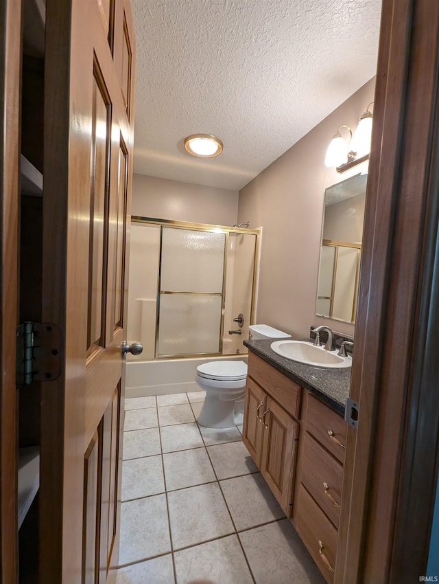 full bathroom featuring vanity, a textured ceiling, shower / bath combination with glass door, toilet, and tile patterned floors