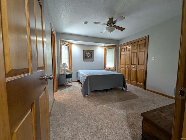 bedroom with ceiling fan, light colored carpet, multiple windows, and a textured ceiling