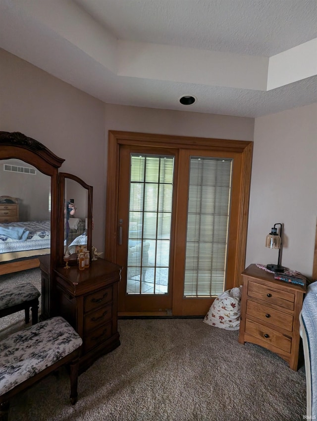 carpeted bedroom with a textured ceiling and a raised ceiling