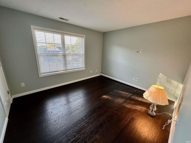 unfurnished room featuring a textured ceiling and dark hardwood / wood-style floors