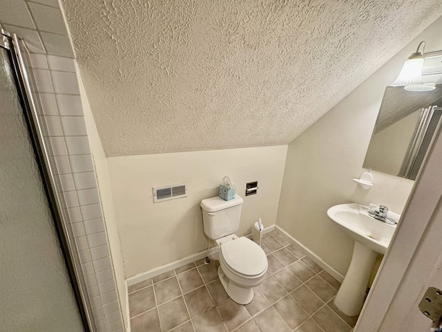 bathroom featuring lofted ceiling, a textured ceiling, tile patterned floors, toilet, and a shower with door