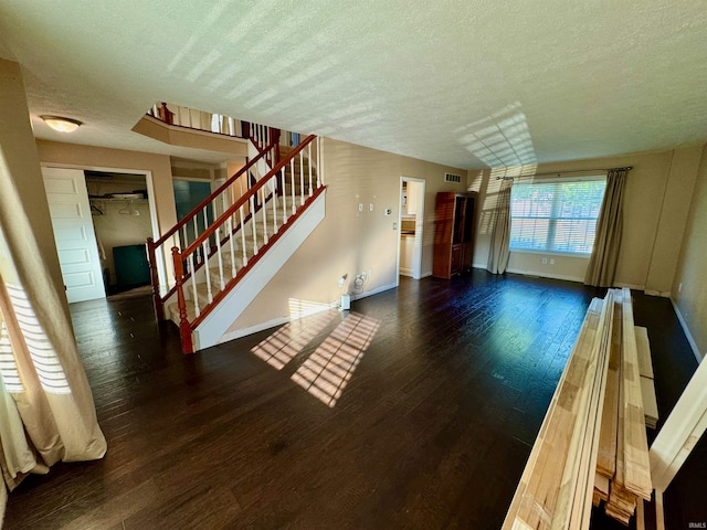 unfurnished living room featuring a textured ceiling and dark wood-type flooring