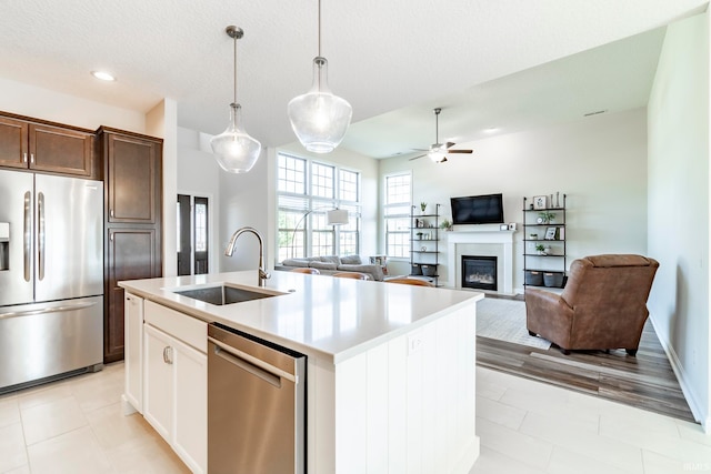 kitchen featuring sink, a center island with sink, appliances with stainless steel finishes, decorative light fixtures, and ceiling fan