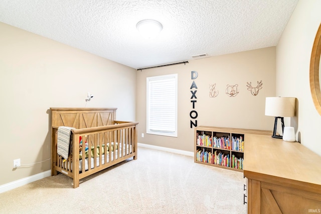 carpeted bedroom featuring a crib and a textured ceiling