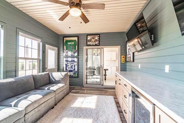 living room featuring wine cooler, wooden walls, dark hardwood / wood-style flooring, ceiling fan, and wooden ceiling