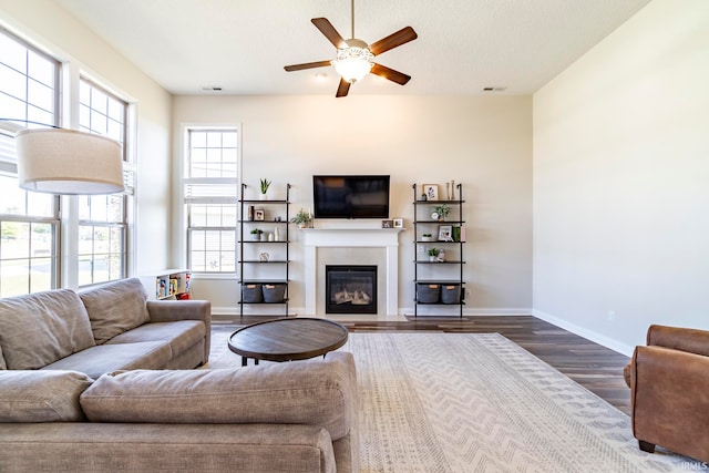 living room with a textured ceiling, a tiled fireplace, ceiling fan, and dark hardwood / wood-style flooring