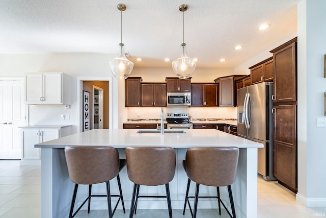 kitchen with pendant lighting, an island with sink, appliances with stainless steel finishes, and sink