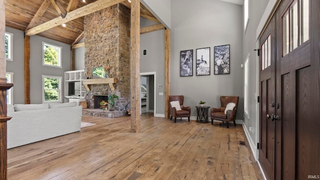 entrance foyer featuring wood ceiling, beam ceiling, wood-type flooring, high vaulted ceiling, and a fireplace