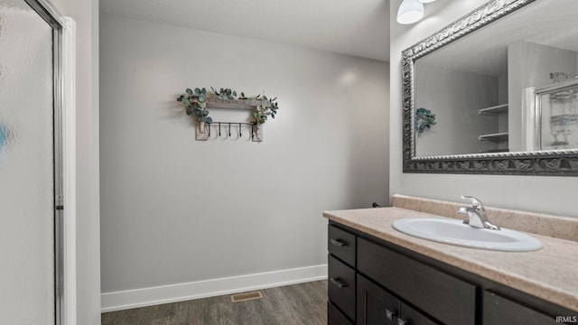 bathroom featuring wood-type flooring, vanity, and a shower with door