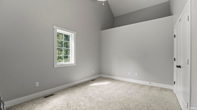 carpeted empty room with ceiling fan and high vaulted ceiling