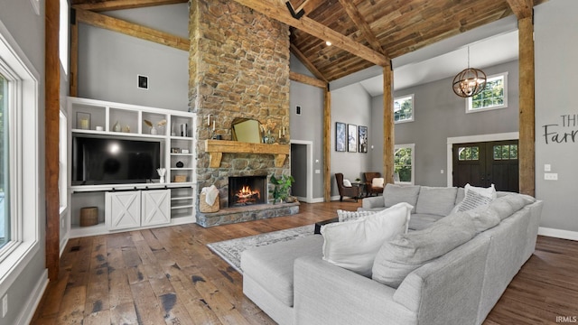 living room with wood-type flooring, high vaulted ceiling, an inviting chandelier, a stone fireplace, and wooden ceiling