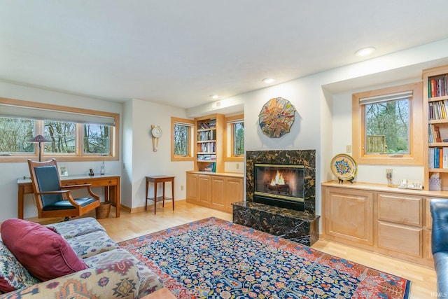 living room featuring light wood-type flooring and a high end fireplace