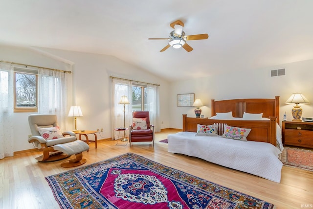 bedroom featuring ceiling fan, vaulted ceiling, multiple windows, and hardwood / wood-style floors