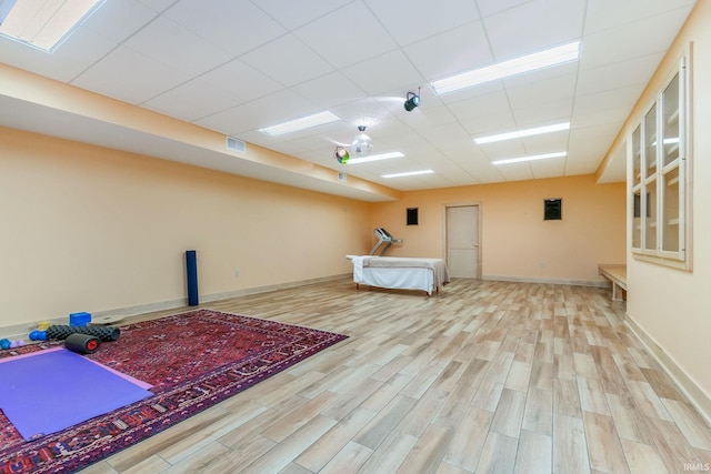 interior space with a drop ceiling and light hardwood / wood-style floors