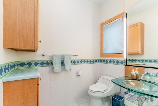 bathroom with tile walls, sink, tile patterned floors, and toilet