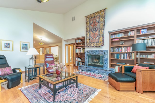 living room with a high ceiling, a premium fireplace, and hardwood / wood-style flooring