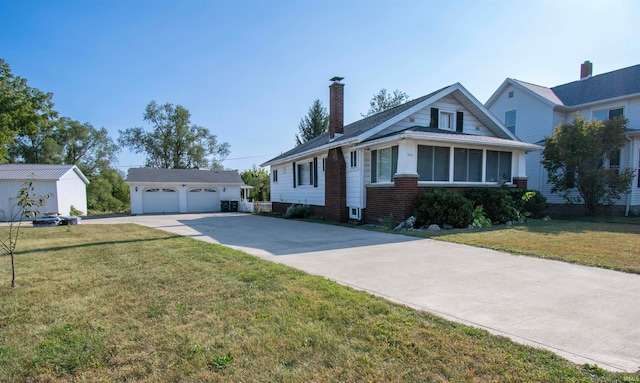 view of front facade featuring a front yard, an outdoor structure, a garage, and a sunroom