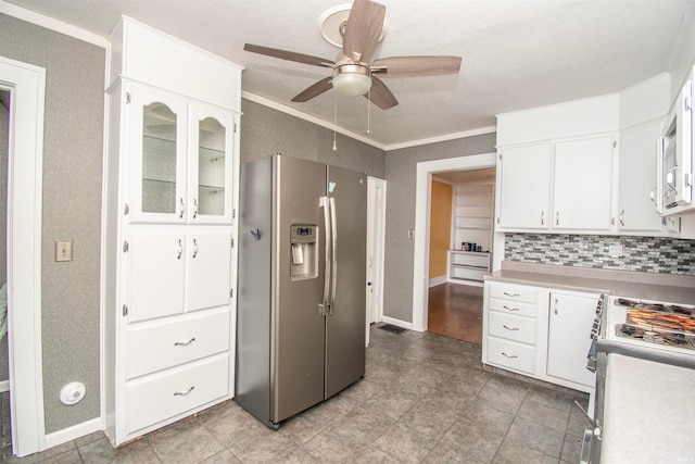 kitchen with stove, tasteful backsplash, stainless steel fridge, white cabinetry, and ornamental molding