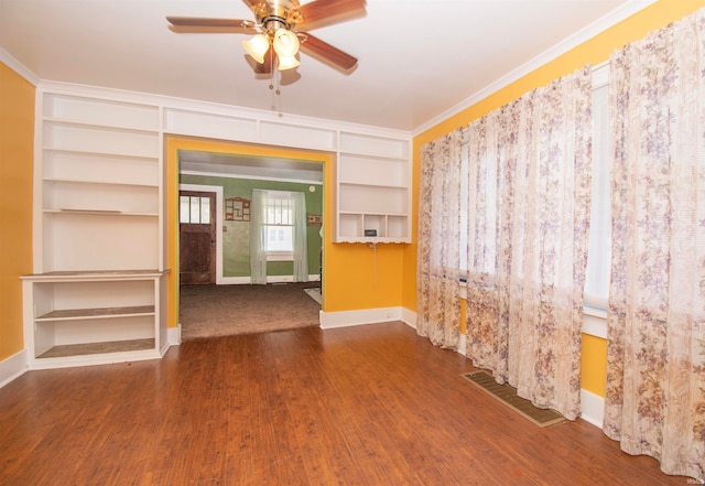 unfurnished room with wood-type flooring, ornamental molding, built in shelves, and ceiling fan