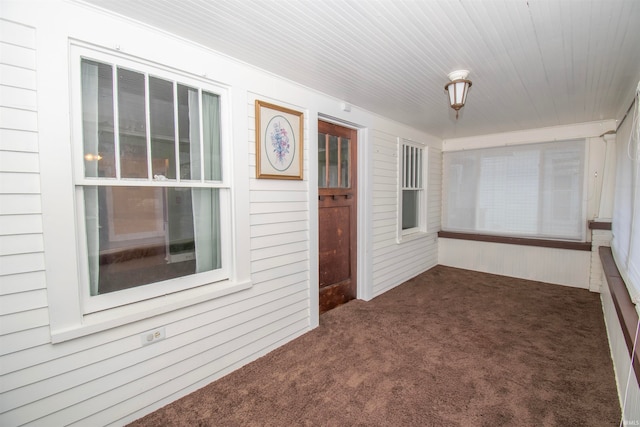 spare room featuring wooden walls and dark colored carpet