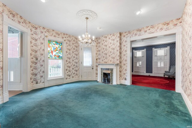 unfurnished living room featuring an inviting chandelier, a high end fireplace, and carpet floors