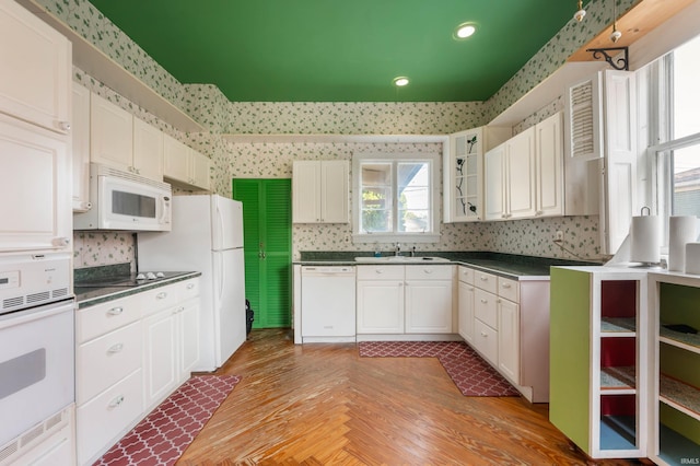 kitchen featuring white cabinets, sink, hardwood / wood-style floors, and white appliances