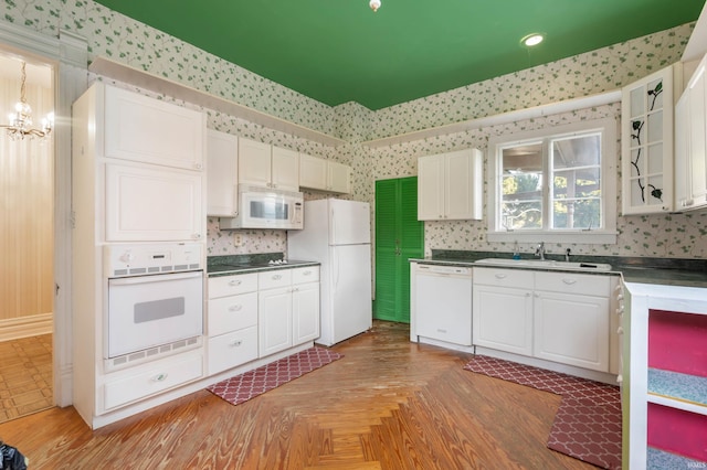 kitchen featuring parquet floors, sink, white appliances, and white cabinetry