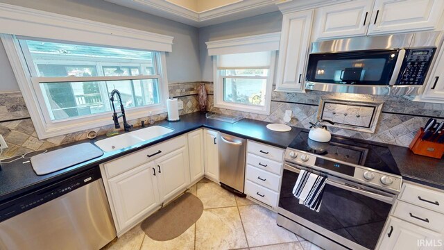 kitchen featuring white cabinets, light tile patterned flooring, stainless steel appliances, crown molding, and decorative backsplash