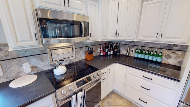10922 N Lower Lakeshore Dr, Monticello, IN 47960 - kitchen featuring dark countertops, white cabinets, decorative backsplash, and stainless steel appliances