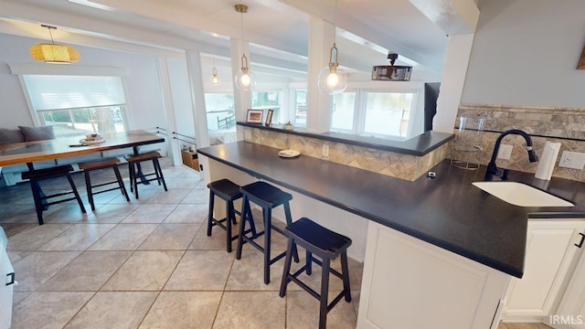 10922 N Lower Lakeshore Dr, Monticello, IN 47960 - kitchen featuring light tile patterned flooring, a sink, a breakfast bar area, tasteful backsplash, and dark countertops