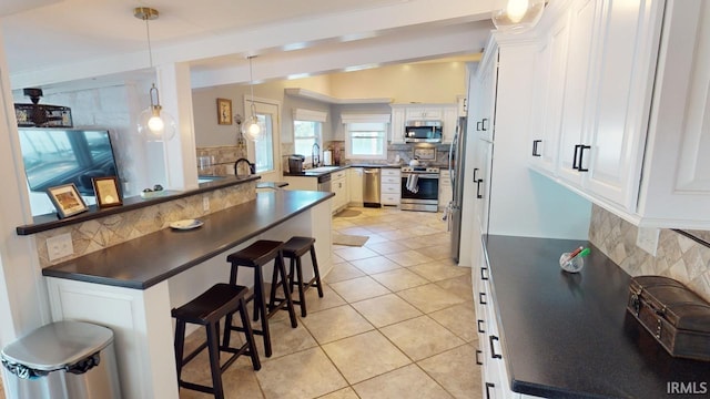 10922 N Lower Lakeshore Dr, Monticello, IN 47960 - kitchen featuring light tile patterned flooring, decorative backsplash, a kitchen bar, stainless steel appliances, and dark countertops