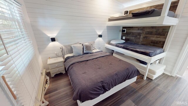 bedroom with wooden walls and dark wood-type flooring