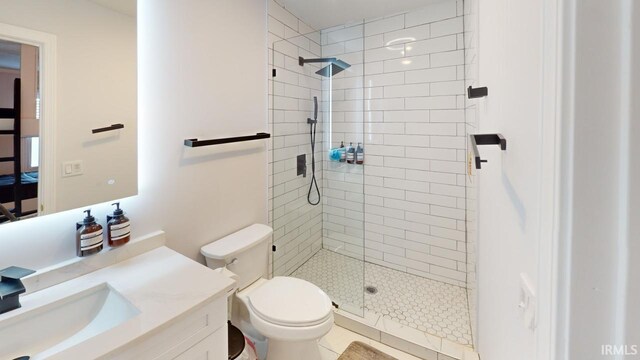 bathroom with tiled shower, vanity, toilet, and tile patterned floors