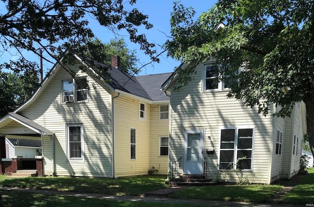 rear view of property with cooling unit and a yard