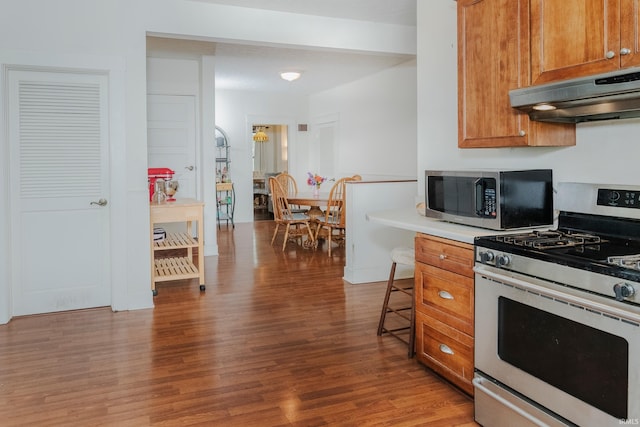 kitchen featuring exhaust hood, stainless steel appliances, a breakfast bar, and light hardwood / wood-style flooring