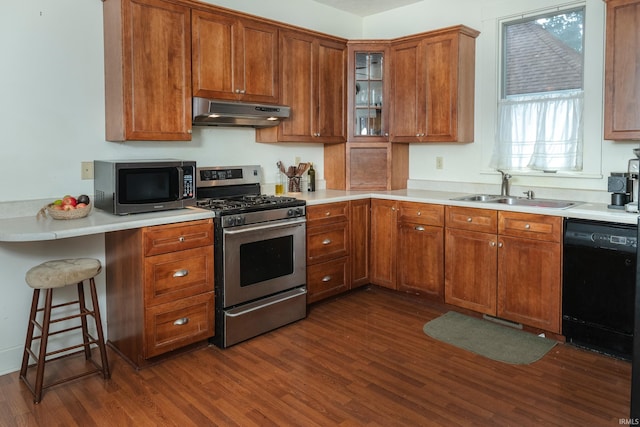 kitchen with a breakfast bar area, sink, extractor fan, stainless steel appliances, and dark hardwood / wood-style flooring