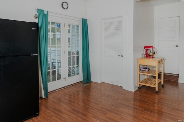 interior space featuring wood-type flooring, black fridge, and access to outside