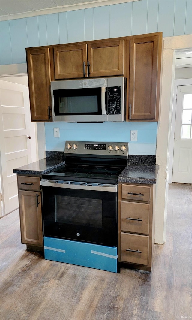 kitchen featuring dark stone countertops, appliances with stainless steel finishes, and hardwood / wood-style flooring