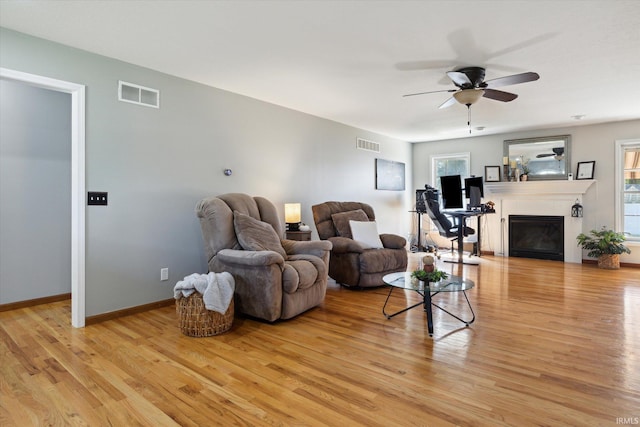 living room featuring light hardwood / wood-style flooring, ceiling fan, and plenty of natural light