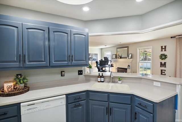 kitchen with blue cabinets, white dishwasher, sink, and kitchen peninsula