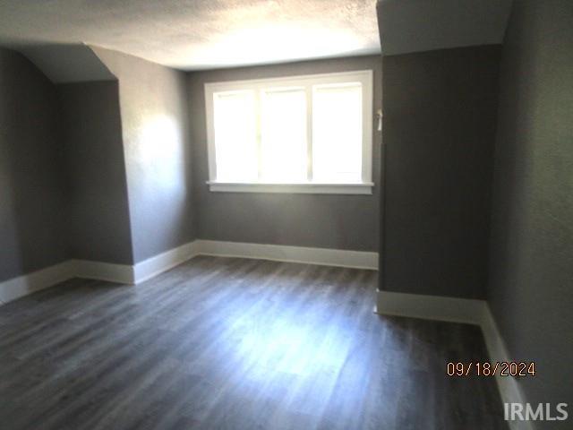 1243 Portage Ave, South Bend, IN 46616 - spare room with baseboards, a textured ceiling, and dark wood-style floors