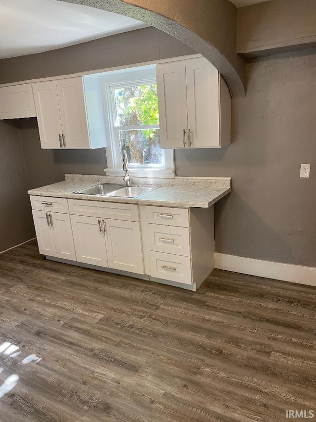 1243 Portage Ave, South Bend, IN 46616 - kitchen featuring baseboards, dark wood-style floors, light countertops, white cabinets, and a sink