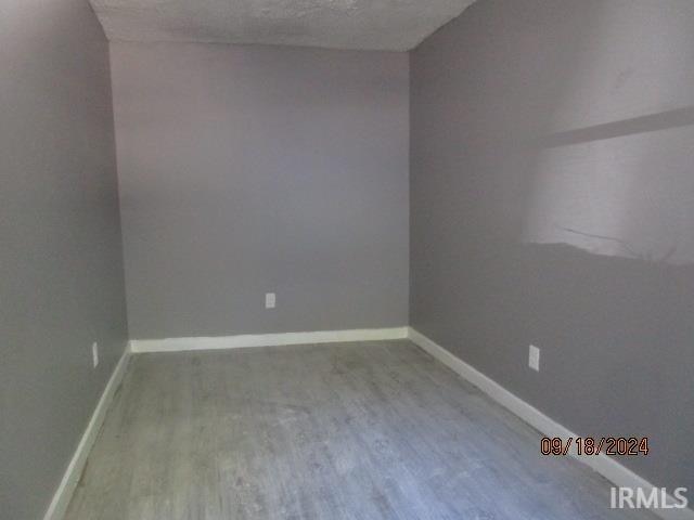 spare room featuring a textured ceiling and hardwood / wood-style floors