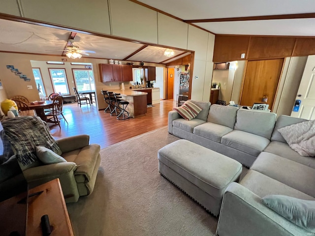 living room featuring light wood-type flooring, lofted ceiling, ceiling fan, and crown molding