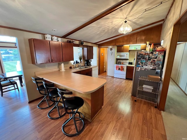 kitchen with lofted ceiling, kitchen peninsula, white appliances, light hardwood / wood-style flooring, and a kitchen breakfast bar