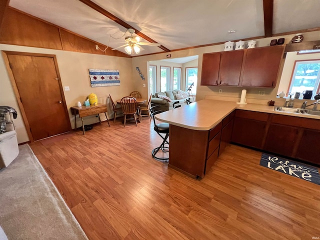 kitchen with ceiling fan, lofted ceiling with beams, kitchen peninsula, and plenty of natural light