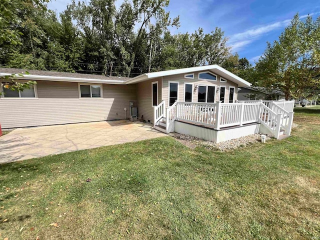 back of property featuring a wooden deck, a yard, and a patio