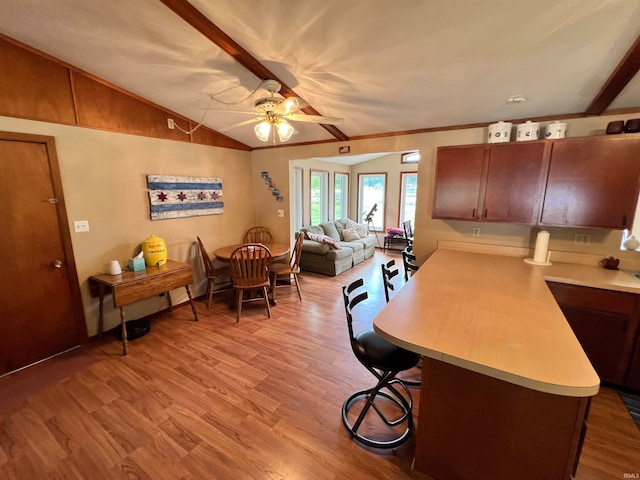 kitchen featuring light wood-type flooring, kitchen peninsula, lofted ceiling with beams, and ceiling fan