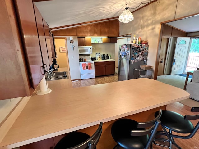 kitchen with sink, lofted ceiling, kitchen peninsula, white appliances, and decorative light fixtures