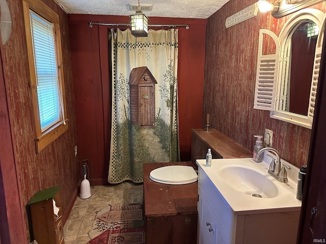 bathroom featuring wood walls, a textured ceiling, and vanity